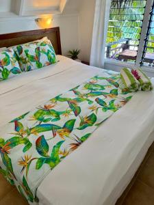阿鲁坦加帕拉蒂斯湾旅舍的一张带白色棉被和多彩蝴蝶的床