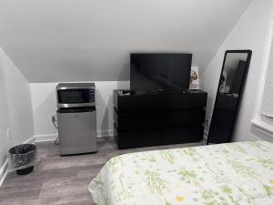 WoodhavenModern & cozy Room in Queens near Train station and buses的一间卧室配有一张床、一台微波炉和一台电视。