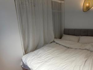 上海Shanghai Hills & CoZy BnB的白色的窗户客房内一张未铺好的床