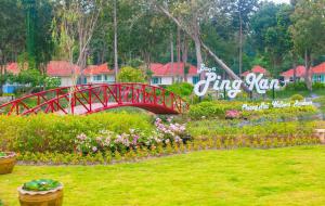 山甘烹Baan Pingkan Wellness Resort的公园里鲜花盛开的花园上的红桥