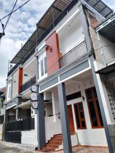 MerganAdor 46 Homestay Syariah & Kost的白色的建筑,设有楼梯和阳台