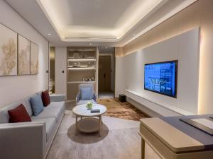 佳木斯Wanda Jin Jiamusi的客厅配有沙发和墙上的电视