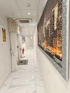 切萨雷奥港HOTEL PARADISE的走廊铺有白色瓷砖地板,墙上挂有绘画作品