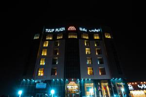 哈费尔巴廷Tulip Plaza Hotel的一座高大的建筑,晚上有灯