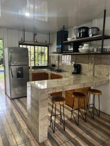 希门尼斯港Villa bonita的厨房配有带凳子的柜台和冰箱。