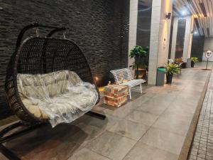 普崇Puchong HELLO KITTY FULLY AIR-CON Suite的一张柳条椅,坐在走廊上,有长凳