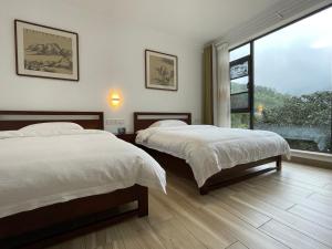 Liyang千岛湖月下民宿的一间卧室设有两张床和大窗户