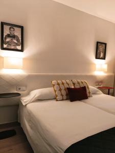 塞维利亚Sevilla Centro Casa Del Pop的卧室配有一张墙上有两张照片的床。