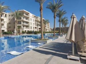 开罗Alumia Marigold Suite 3BR Apt Pool Access的一座拥有棕榈树和遮阳伞的游泳池