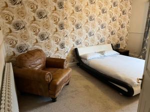 利物浦Contractors accommodation near John Lennon Airport的一间卧室配有一张床和一把椅子,墙上挂着玫瑰花