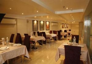 新德里Hotel Palm Do'r Near New Delhi Railway Station的餐厅配有桌椅和白色桌布