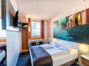 弗莱堡弗赖堡诺德早餐加住宿酒店的卧室配有一张床,墙上挂有绘画作品