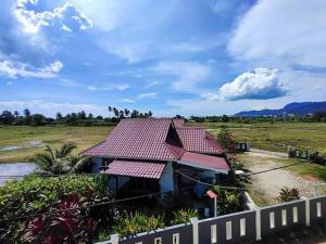 瓜埠Langkawi Homestay Bunga Padi的田野上红色屋顶的房子