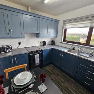 斯托诺韦BAYVIEW的厨房配有蓝色橱柜、桌子和水槽