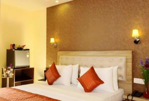 新德里Hotel Aeroporto Near By Delhi International Airport的一间卧室配有带橙色和白色枕头的床
