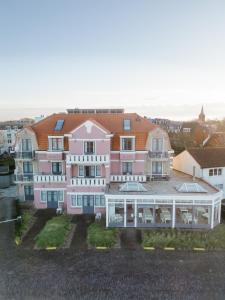栋堡博世徐恩酒店的一座大型粉红色房子,前面设有阳台