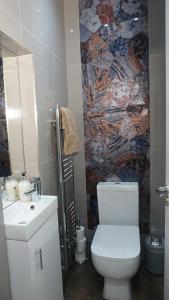 伦敦Luxury London house sleeps 13, 2 minutes to metro的浴室设有白色卫生间和马赛克墙。