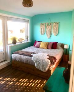弗利辛恩Costa Linda B&B的一间卧室配有一张蓝色墙壁的床和一扇窗户