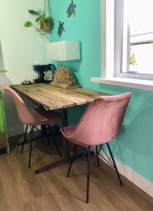 弗利辛恩Costa Linda B&B的一张木桌,里面摆放着两把粉红色的椅子