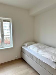 桑内斯Nydelig perle rett ved fjorden的白色客房的一张床位,设有窗户