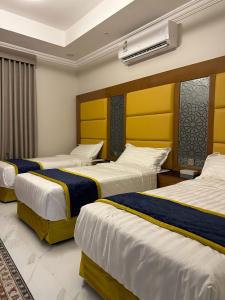 塔伊夫HOLIDAy فاملي الطائف的酒店客房,设有三张床,配有黄色和蓝色的床单