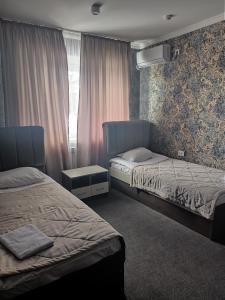 塔拉兹ЭДЕМ的一间卧室设有两张床和窗户。