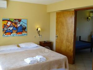 德尔迪阿布罗角阿酷乐啦酒店的一间卧室设有两张床,墙上挂着一幅画