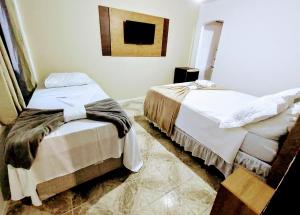 安格拉杜斯雷斯Pousada da Praia的一间卧室设有两张床,墙上挂着一幅画