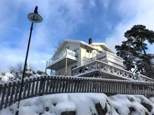 DalaröHärlig Skärgårdsvilla med strålande sjöutsikt的雪覆盖的房屋,有栅栏和街灯