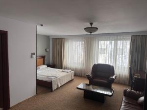 布加勒斯特Hotel Bliss的配有一张床和一把椅子的酒店客房