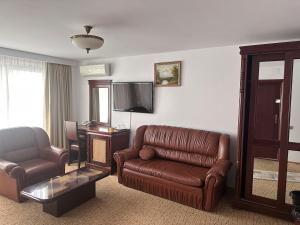 布加勒斯特Hotel Bliss的客厅配有真皮沙发和椅子