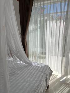 Vinh HoaRobinson Beach Bungalow的一张带白色天蓬和窗户的床