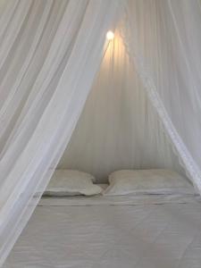 Vinh HoaRobinson Beach Bungalow的一张带天蓬的白色床和两个枕头