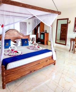 蓬圭Karibu Beach Resort的一间卧室配有一张带天蓬的大床