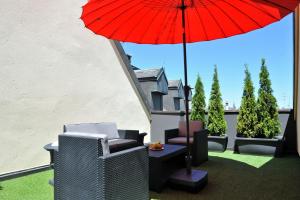 日内瓦欧派斯酒店的一个带红色遮阳伞和椅子及桌子的庭院