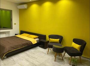 MornagVilla avec piscine et Jacuzzi Tunis的一间卧室设有一张床和两把椅子,还有一面黄色的墙壁