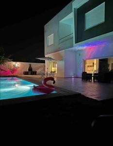 MornagVilla avec piscine et Jacuzzi Tunis的一座晚上设有游泳池的房子