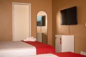 布希奥斯Porteño Loft Búzios的客房设有两张床、一台冰箱和一台平面电视。