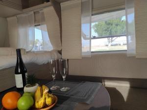提比里亚טבע של קרוואן的一间设有一张桌子的房间,配有两杯葡萄酒和水果
