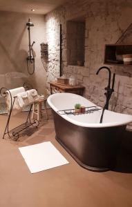 维尔雅尔姆Le Lodge des Flâneurs的石墙客房内的浴缸