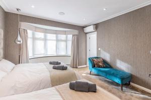 伦敦Mansion with jacuzzi in London 7 min from Station的一间卧室配有两张床和蓝色的沙发