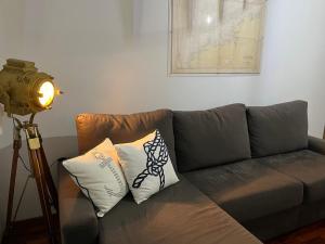 桑亨霍Apartamento NaVega Sanxenxo的一张带枕头的沙发旁的三脚架上的摄像头