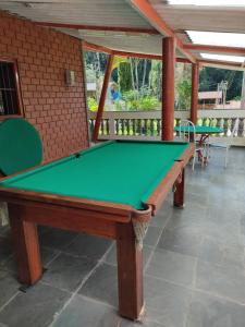 瓜鲁柳斯Chácara, 3 suítes, piscina, lago, wi-fi 250 mbps的一张绿色台球桌,房间带两张桌子