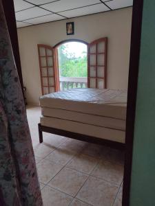 瓜鲁柳斯Chácara, 3 suítes, piscina, lago, wi-fi 250 mbps的一间卧室设有一张床和一个开放式窗户。