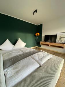 科堡FeWo Max Nähe HUK, neu eingerichtet und renoviert的一间卧室设有一张大床和绿色的墙壁