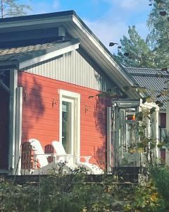 HuutotöyryVuolenkosken Helmi - laadukas ympärivuotinen kohde的门廊上带两把椅子的红色房子