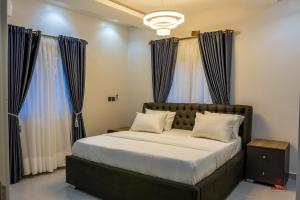 阿布贾99 MOZILLA APARTMENTS AND SUITES的一间卧室配有一张带蓝色窗帘的大床