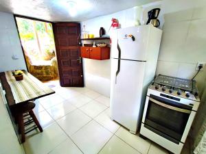 伊利亚贝拉Chalé da cachoeira - Ilhabela的厨房配有白色冰箱和炉灶。