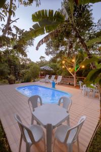 普拉亚多Aruana Suites Tranquilidade e Sossego no meio da Natureza a 5km da Vila de Praia do forte的池畔露台配有桌椅