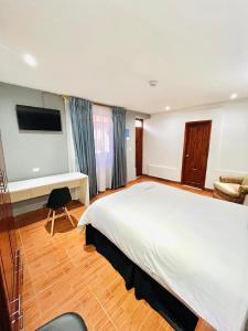 伊瓦拉Quinta San Carlos Hostel的卧室配有一张白色大床和一张书桌